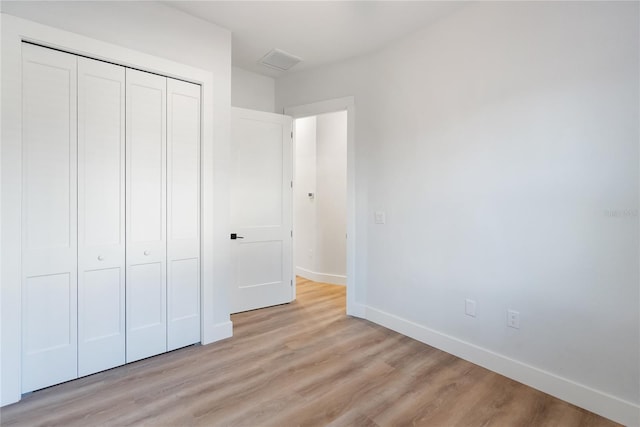 unfurnished bedroom with a closet and light wood-type flooring