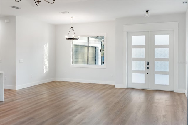 foyer with wood-type flooring, french doors, and an inviting chandelier