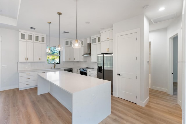 kitchen with white cabinets, backsplash, appliances with stainless steel finishes, and a center island