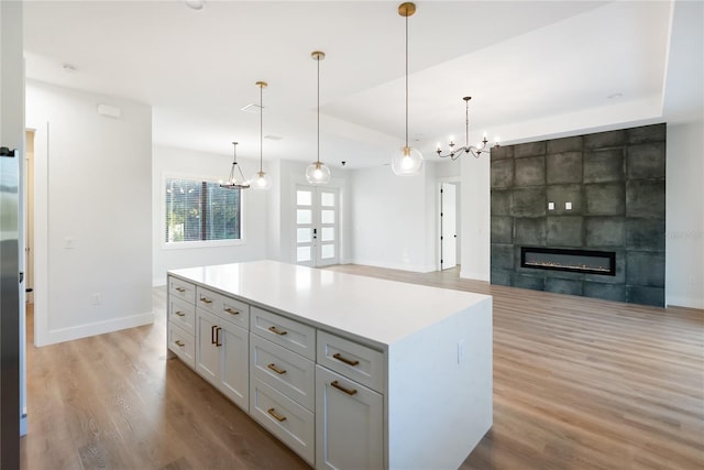 kitchen with decorative light fixtures, a center island, a raised ceiling, and a fireplace