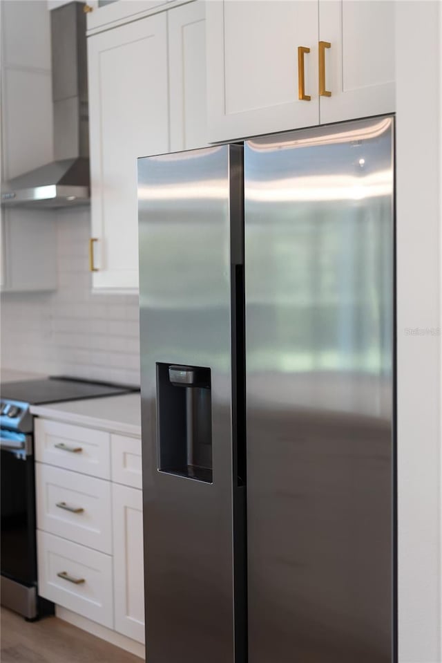 kitchen featuring stainless steel appliances, wall chimney exhaust hood, white cabinets, and tasteful backsplash