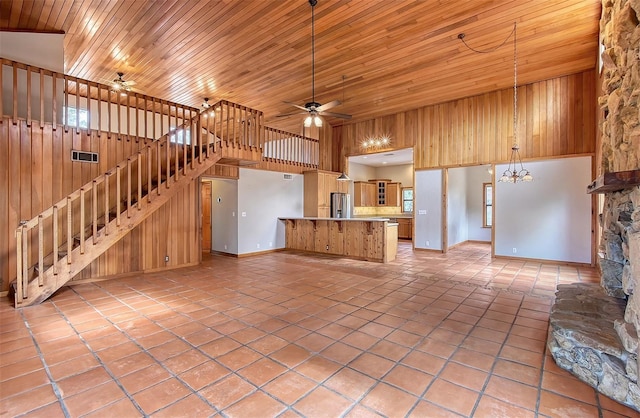 unfurnished living room featuring ceiling fan with notable chandelier, a high ceiling, and wooden ceiling