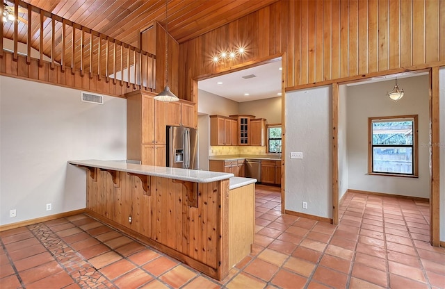 kitchen with decorative light fixtures, kitchen peninsula, a kitchen breakfast bar, stainless steel appliances, and light tile patterned floors