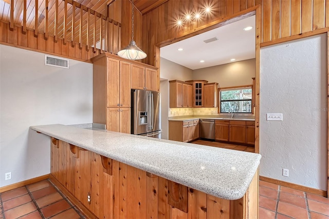 kitchen featuring decorative light fixtures, kitchen peninsula, stainless steel appliances, and light tile patterned flooring