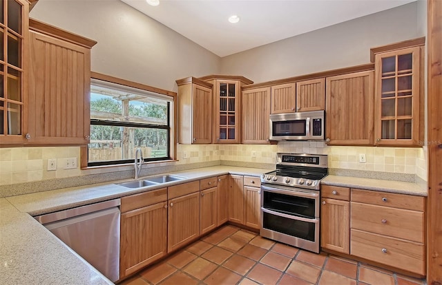 kitchen featuring sink, backsplash, stainless steel appliances, and light tile patterned flooring