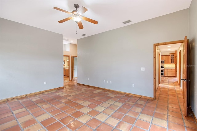 empty room with ceiling fan and light tile patterned floors