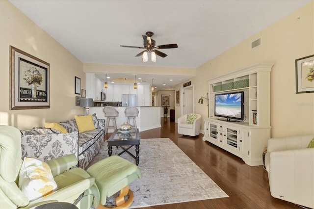 living room with ceiling fan and dark wood-type flooring