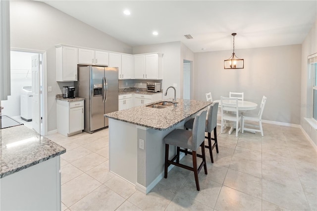 kitchen with sink, stainless steel fridge with ice dispenser, white cabinetry, and light stone countertops