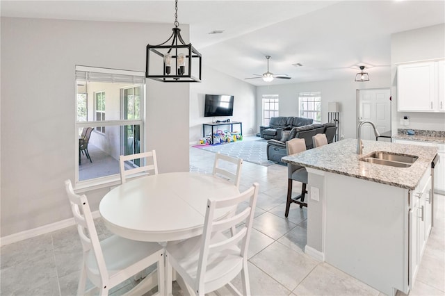 tiled dining room featuring sink, lofted ceiling, and ceiling fan with notable chandelier