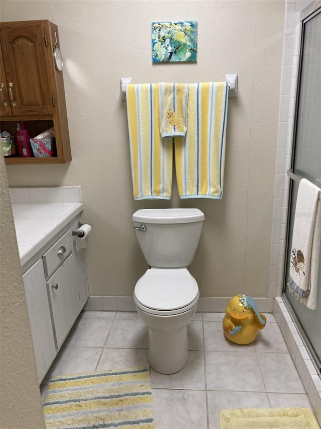 bathroom featuring toilet, tile patterned floors, walk in shower, and vanity