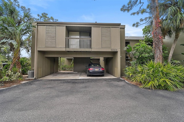 view of front of house with central AC unit, a balcony, and covered parking