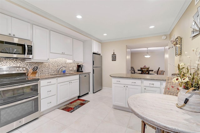 kitchen featuring a sink, appliances with stainless steel finishes, white cabinetry, crown molding, and tasteful backsplash