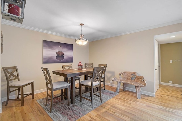 dining space featuring crown molding, baseboards, and light wood-type flooring