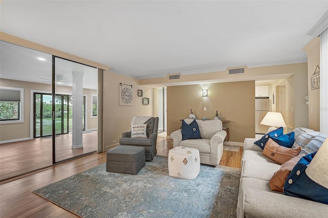 living area featuring visible vents, crown molding, and wood finished floors