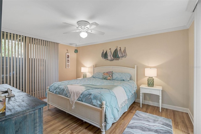 bedroom with a ceiling fan, crown molding, wood finished floors, and baseboards