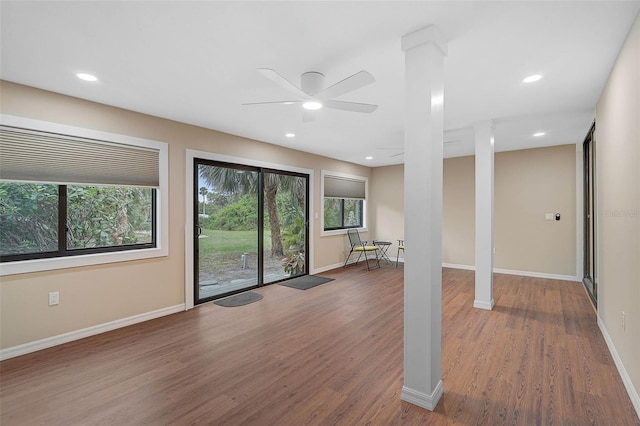 interior space featuring ceiling fan, wood-type flooring, and ornate columns