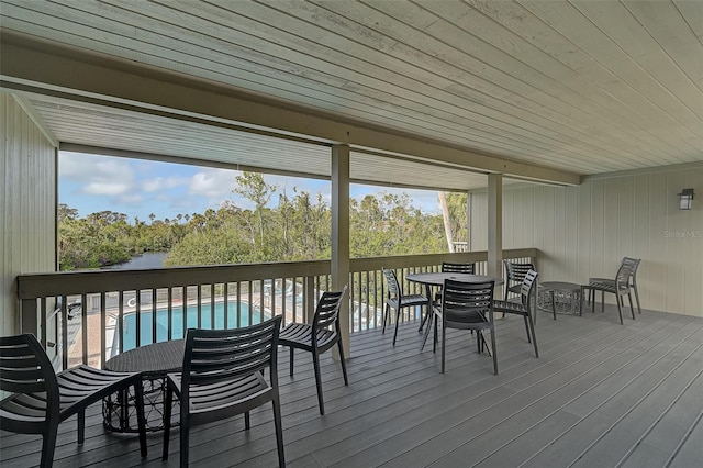 deck with outdoor dining space and an outdoor pool