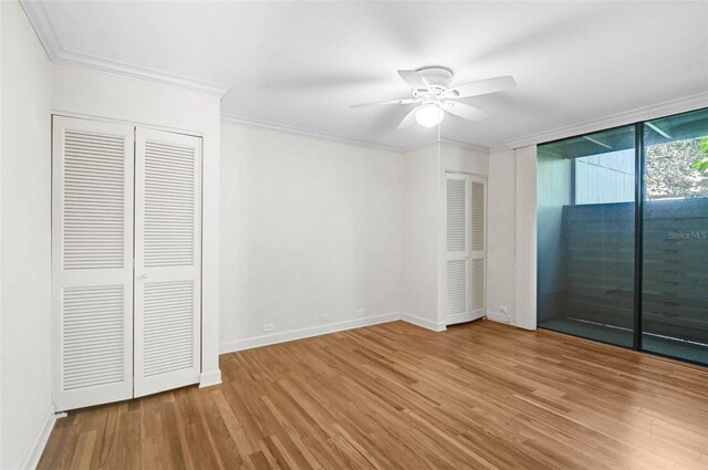 304 Pine Run Dr, Osprey, FL 34229 - unfurnished bedroom featuring access to exterior, wood finished floors, baseboards, ornamental molding, and multiple closets