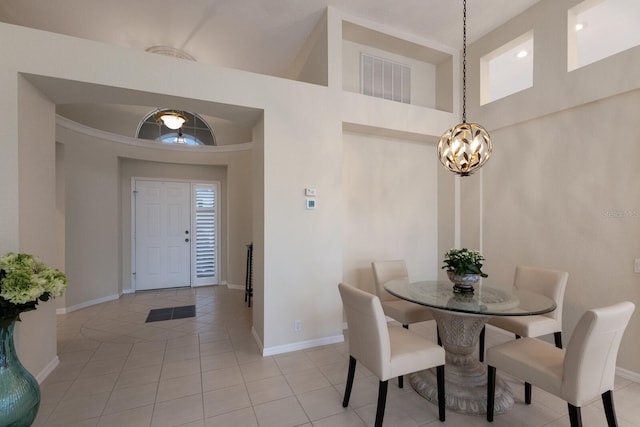 dining room with a towering ceiling, light tile patterned floors, and a notable chandelier