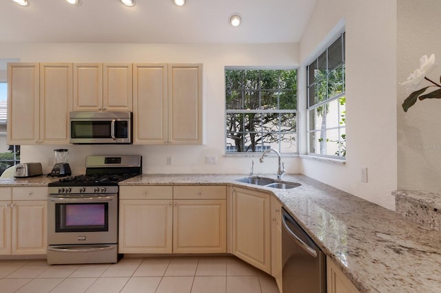 kitchen with sink, light stone counters, stainless steel appliances, and light tile patterned flooring