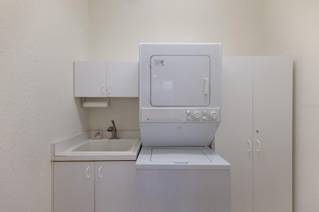 laundry room with stacked washer / drying machine, sink, and cabinets