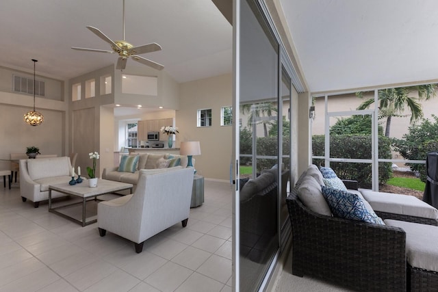 tiled living room featuring a towering ceiling and ceiling fan with notable chandelier