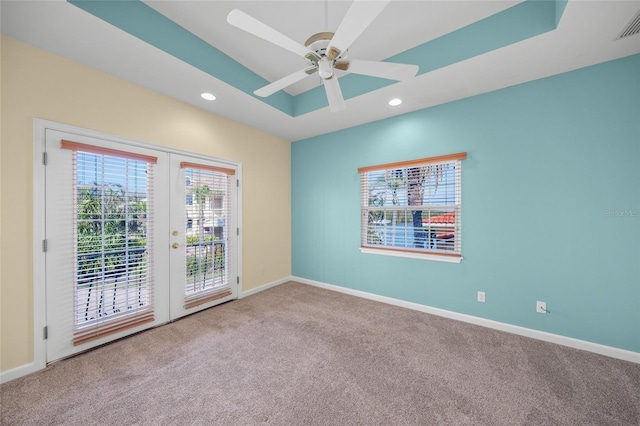 empty room featuring ceiling fan, carpet, a raised ceiling, and french doors