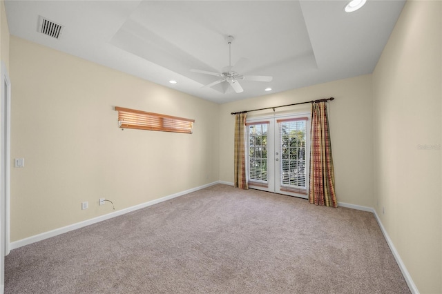 carpeted spare room with ceiling fan and a raised ceiling