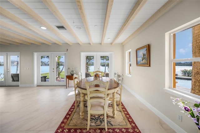 dining room featuring a water view, beam ceiling, and french doors