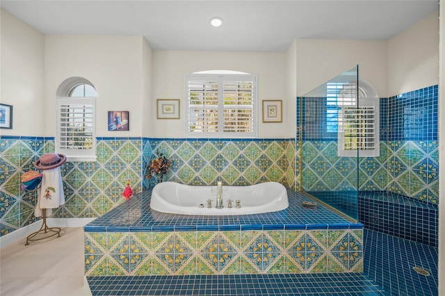 bathroom with tile walls, tile patterned floors, and tiled tub