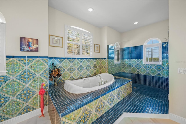 bathroom featuring tiled bath, tile patterned flooring, tile walls, and plenty of natural light