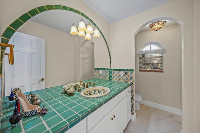 bathroom featuring toilet, backsplash, and vanity