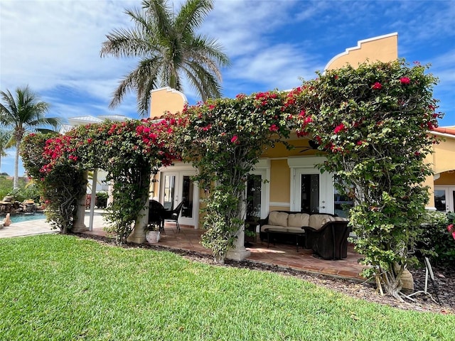 view of front of property with a front lawn, a patio area, an outdoor living space, and french doors