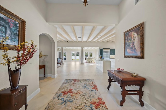 hall featuring ornate columns, light tile patterned floors, and beamed ceiling