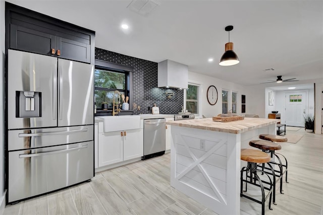 kitchen featuring a center island, decorative light fixtures, stainless steel appliances, white cabinets, and ceiling fan