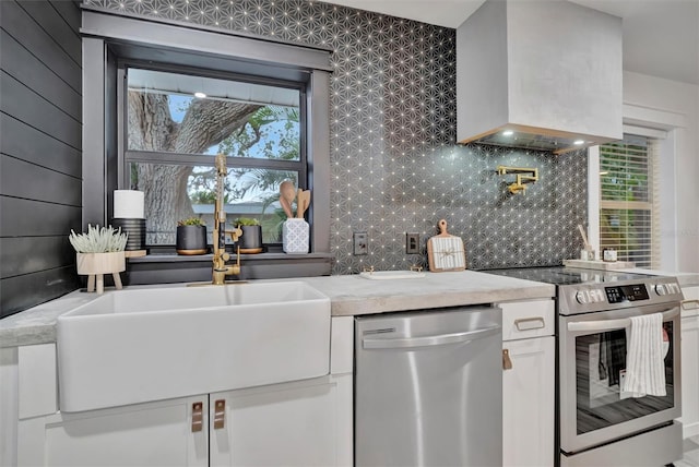 kitchen with stainless steel appliances, sink, white cabinets, custom range hood, and backsplash