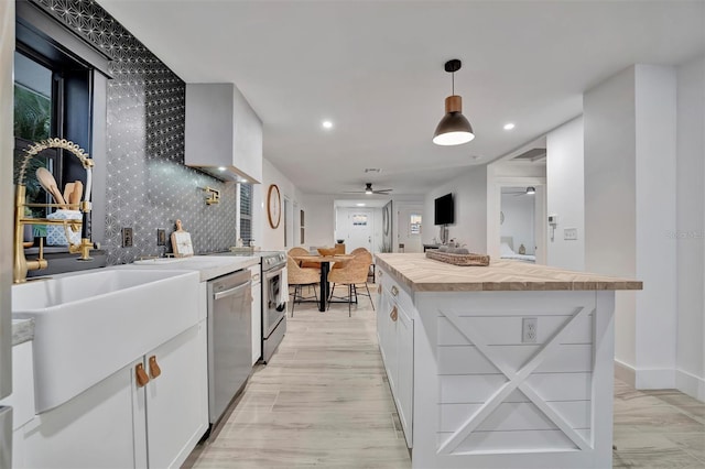 kitchen with appliances with stainless steel finishes, a center island, ceiling fan, white cabinets, and decorative light fixtures