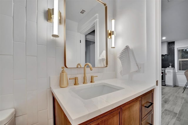 bathroom with toilet, backsplash, and vanity