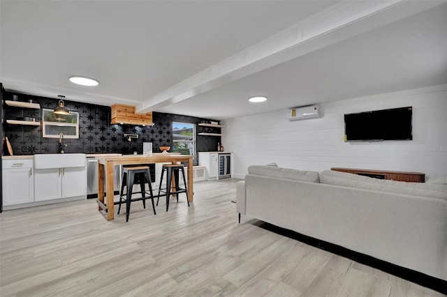 living room with sink, light wood-type flooring, and a wall mounted air conditioner