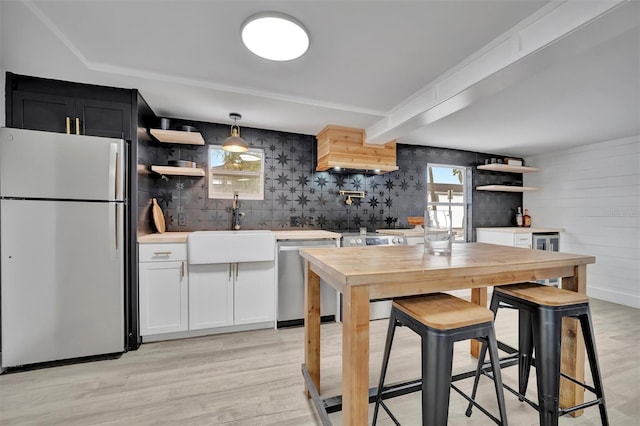 kitchen featuring sink, white cabinets, light hardwood / wood-style floors, pendant lighting, and appliances with stainless steel finishes