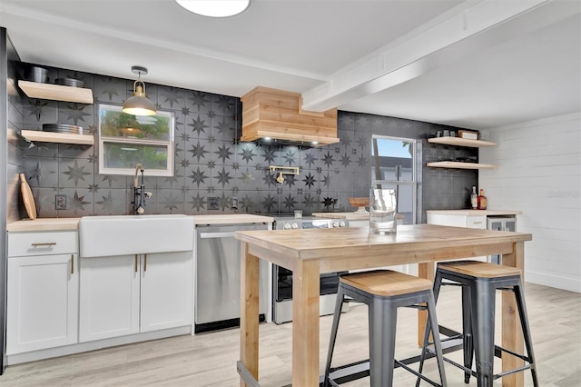 kitchen with stainless steel appliances, sink, white cabinets, light hardwood / wood-style flooring, and hanging light fixtures