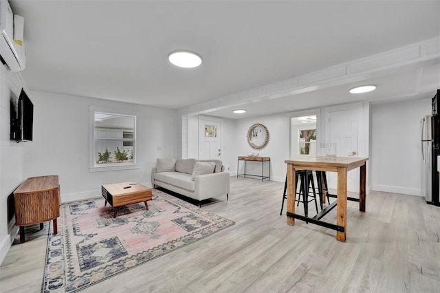 living room with a wall unit AC and light hardwood / wood-style flooring