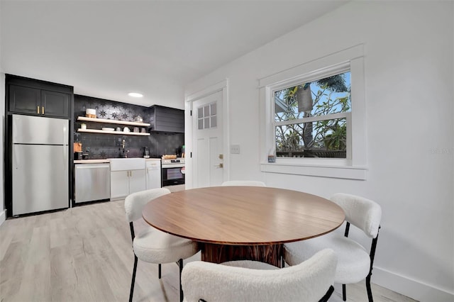 dining area with light hardwood / wood-style floors and wet bar