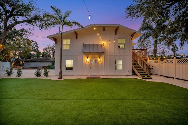 back house at dusk featuring a lawn