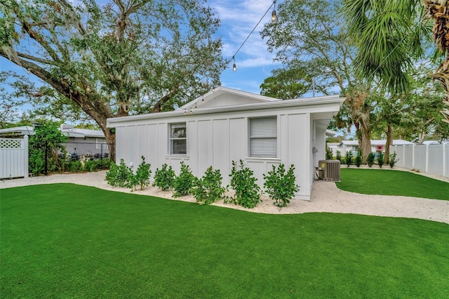 rear view of property featuring central air condition unit and a lawn