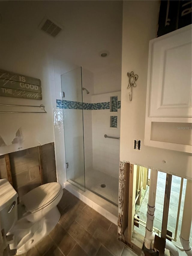 bathroom featuring toilet and a shower with door