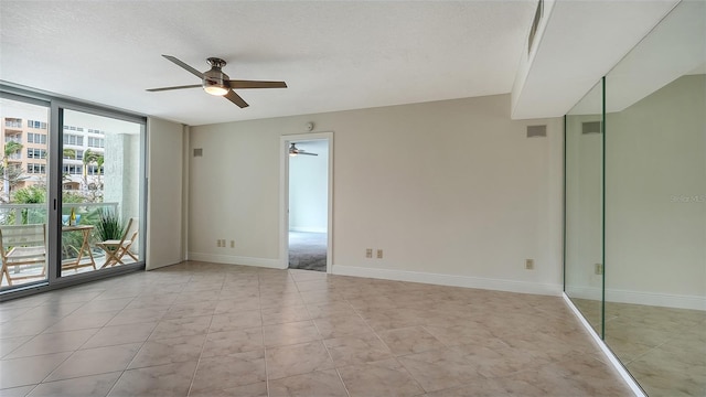 empty room featuring ceiling fan, a textured ceiling, and expansive windows