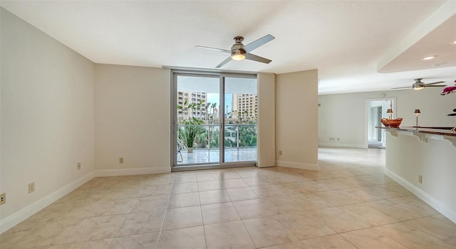 tiled empty room with ceiling fan and a wall of windows