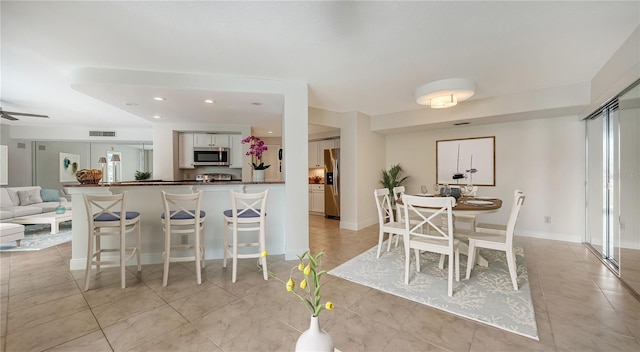 kitchen with white cabinets, stainless steel appliances, kitchen peninsula, ceiling fan, and light tile patterned floors