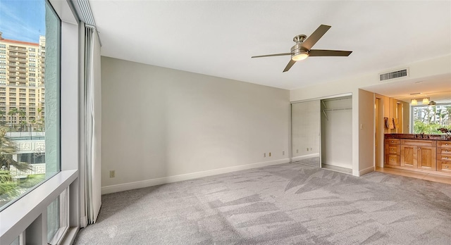 unfurnished bedroom with ceiling fan, a closet, and light colored carpet